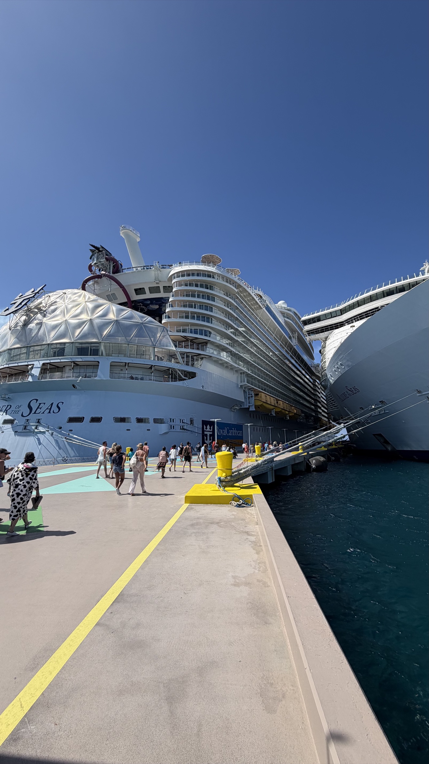 Two Royal Caribbean Oasis-class ships docked side by side at a pier