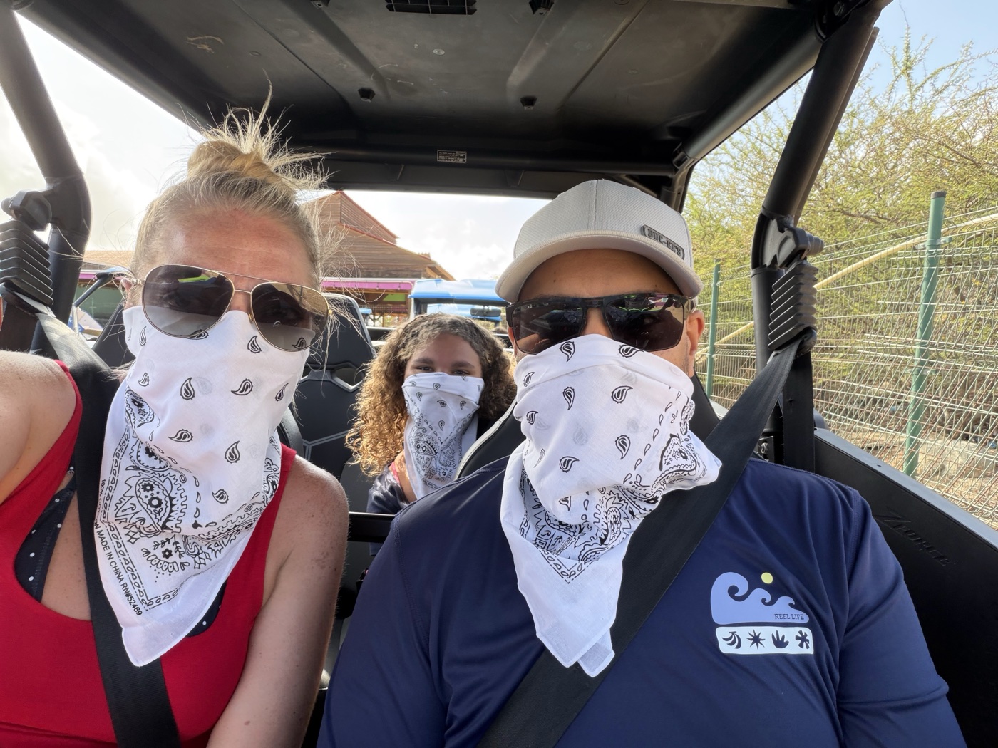 Three of us in a UTV wearing bandanas as dust masks on the Aruba off-road tour