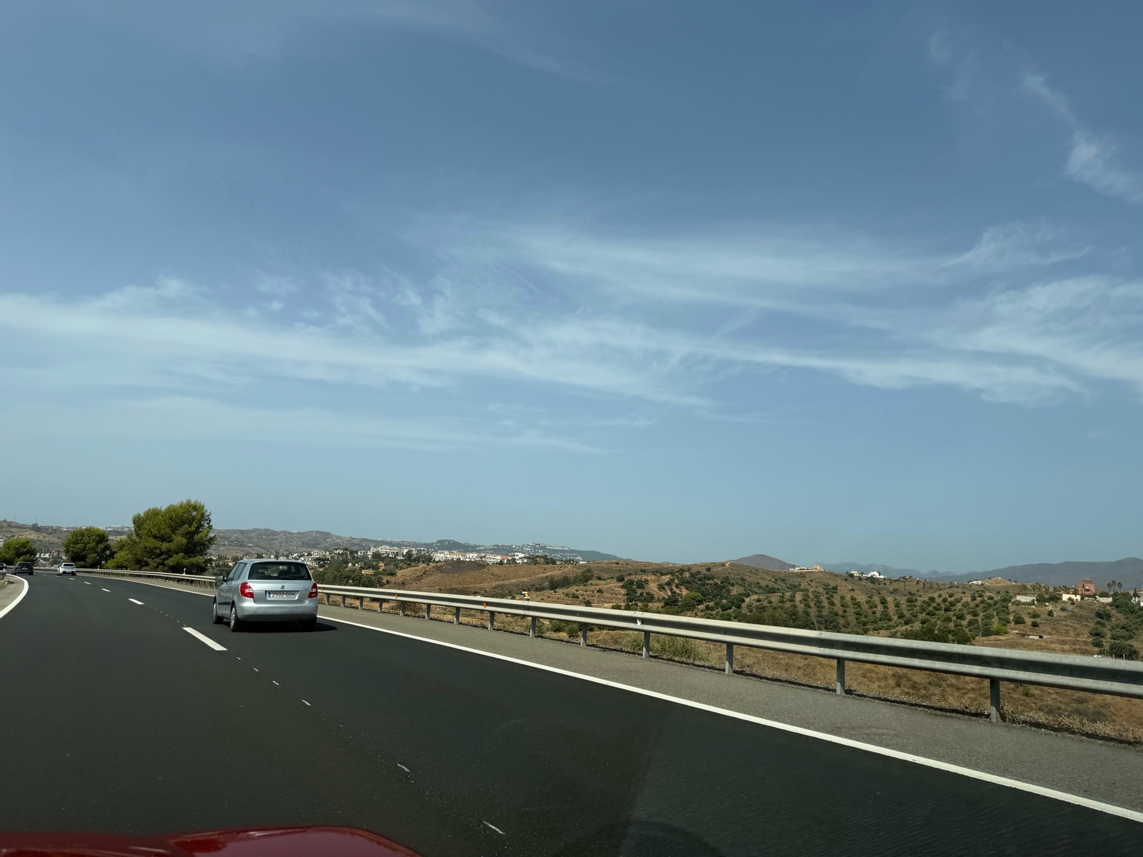 The coast road running through dry hills, other traffic ahead