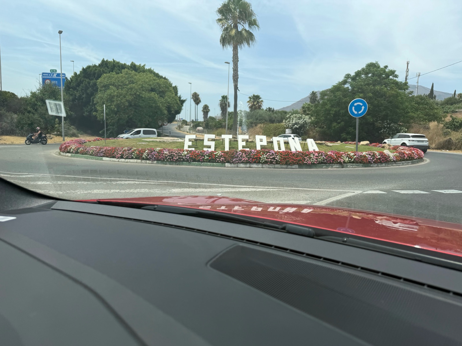 The Estepona sign on a flower-planted roundabout, seen from the car