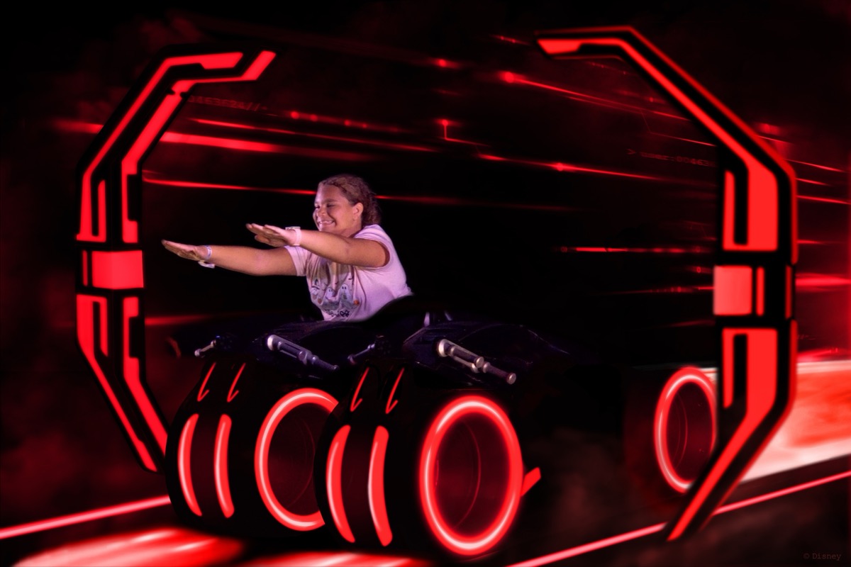 Abigail mid-ride on Tron Lightcycle Run, leaning into the red neon light tunnel