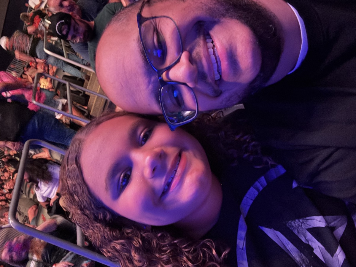 Miguel and Abigail selfie at a live event with arena lighting
