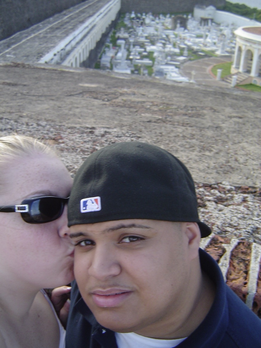 Newlyweds at El Morro overlooking Old San Juan, kiss on the cheek