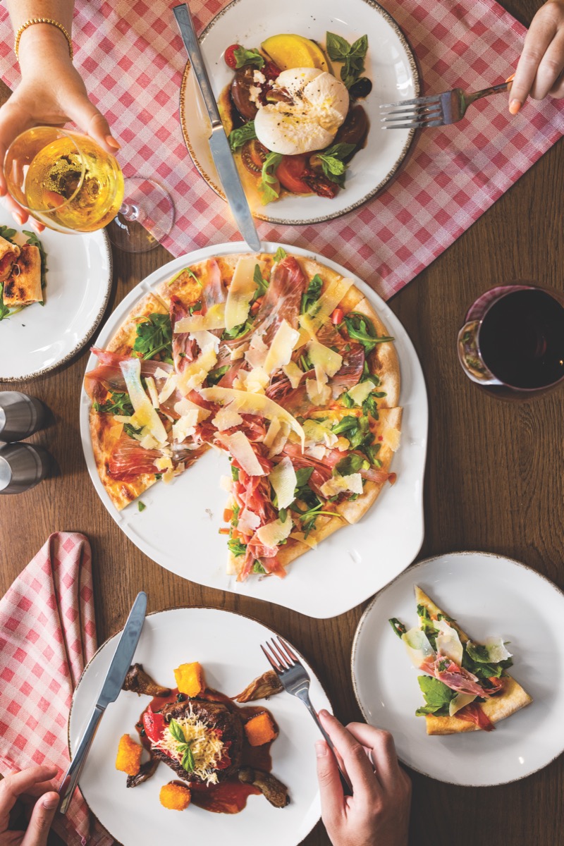Pizza with prosciutto and arugula, burrata salad, and braised dish at Giovanni's Italian Kitchen