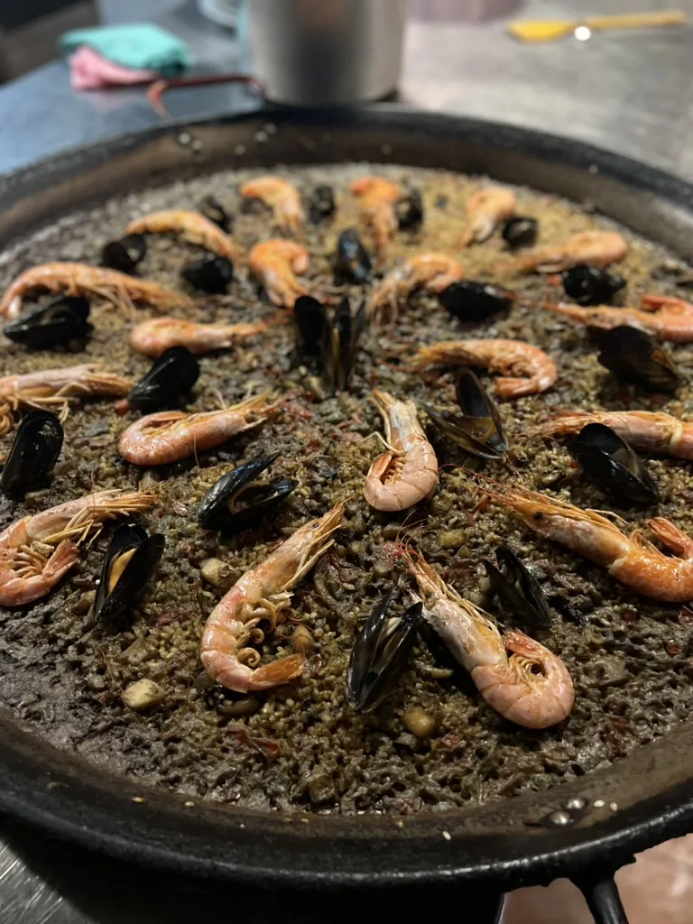 Finished black paella topped with prawns and mussels