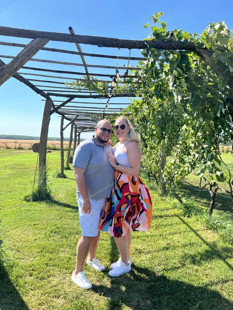Miguel and Ashley under a vine-covered pergola at a Tuscan farmhouse