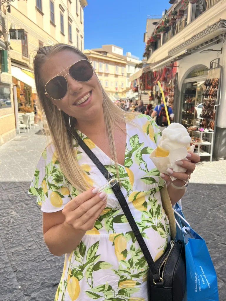 Ashley in a lemon-print dress holding a lemon treat on a street in Amalfi